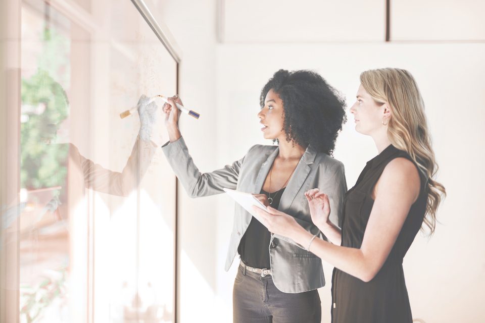 Two colleagues planning at a whiteboard