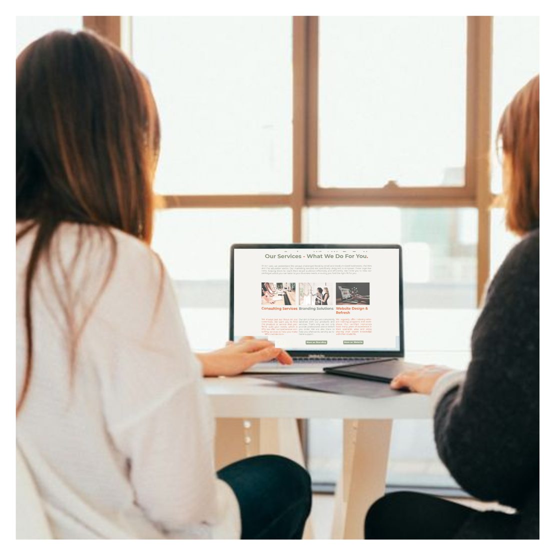 Woman working on a website at a laptop by a window
